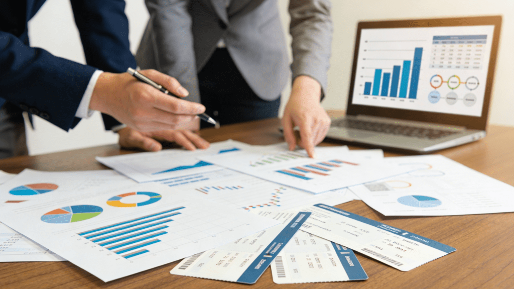 Two professionals reviewing financial charts, bar graphs, and travel documents to calculate the ROI of modern trip management.