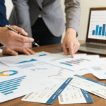 Two professionals reviewing financial charts, bar graphs, and travel documents to calculate the ROI of modern trip management.